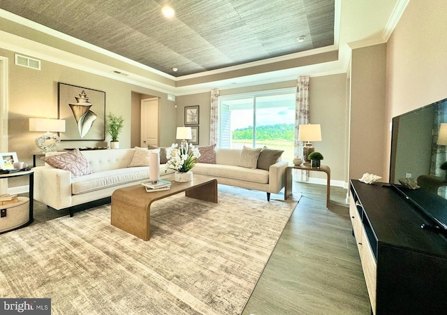 living room with a tray ceiling, ornamental molding, and hardwood / wood-style floors