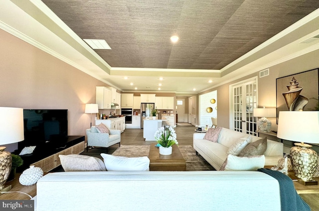 living room with a raised ceiling, french doors, dark wood-type flooring, and ornamental molding