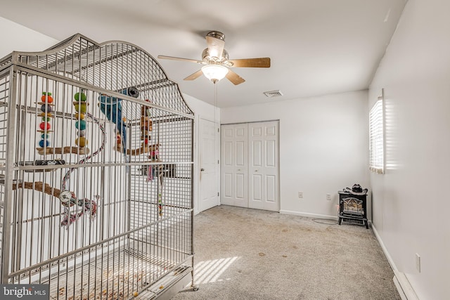 interior space with carpet floors, a wood stove, a closet, and ceiling fan