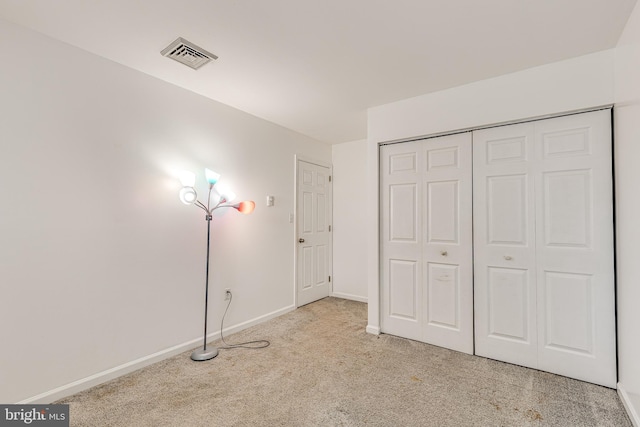 unfurnished bedroom with a closet and light colored carpet