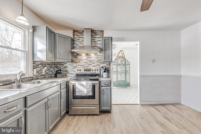 kitchen with pendant lighting, wall chimney exhaust hood, tasteful backsplash, sink, and stainless steel electric range oven