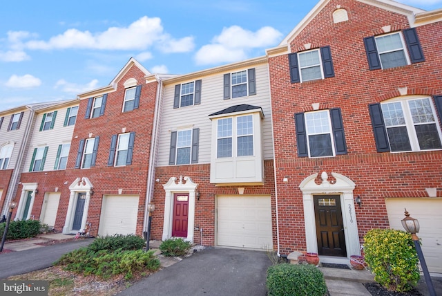 multi unit property with a garage, brick siding, and driveway