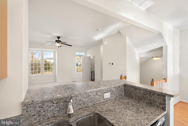 kitchen featuring a ceiling fan, baseboards, a sink, and light wood finished floors