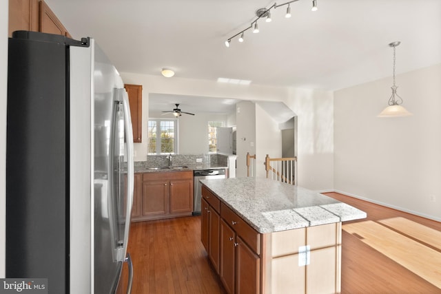 kitchen with stainless steel appliances, a sink, a kitchen island, open floor plan, and pendant lighting