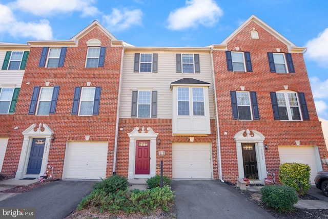 multi unit property featuring driveway, brick siding, and an attached garage