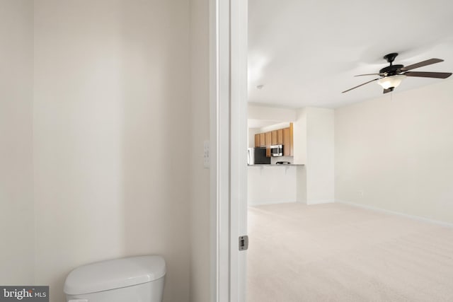 bathroom featuring a ceiling fan, toilet, and baseboards