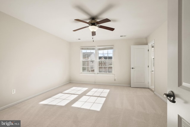 spare room featuring light carpet, ceiling fan, visible vents, and baseboards