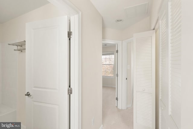 hall with light colored carpet, visible vents, and baseboards