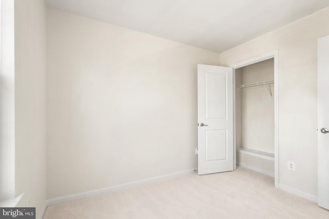 unfurnished bedroom with baseboards, a closet, and light colored carpet