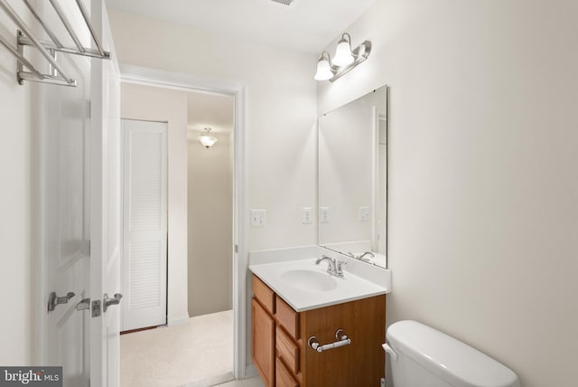 half bathroom featuring toilet, a closet, and vanity