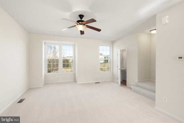 empty room featuring baseboards, ceiling fan, visible vents, and light colored carpet