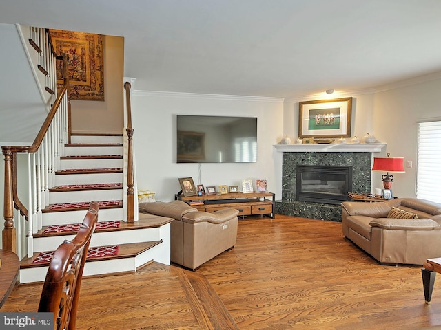 living room with hardwood / wood-style flooring, a high end fireplace, and crown molding