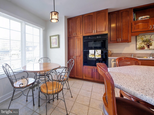 kitchen featuring light tile patterned floors, black double oven, light stone counters, and hanging light fixtures