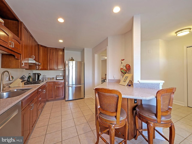 kitchen featuring light tile patterned floors, stainless steel appliances, kitchen peninsula, and sink