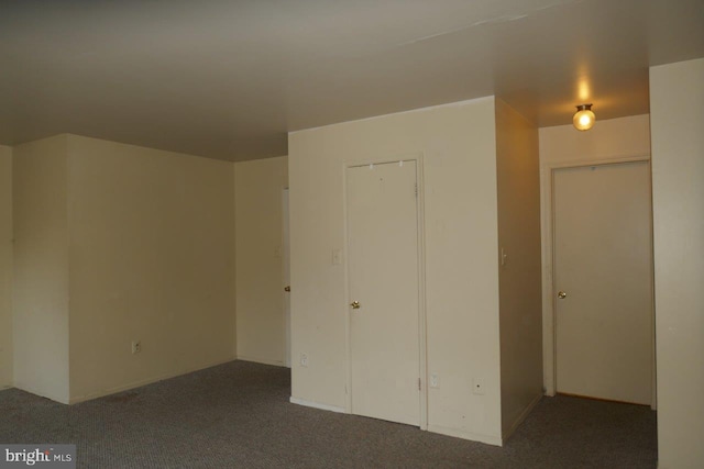 interior space featuring dark colored carpet and a closet