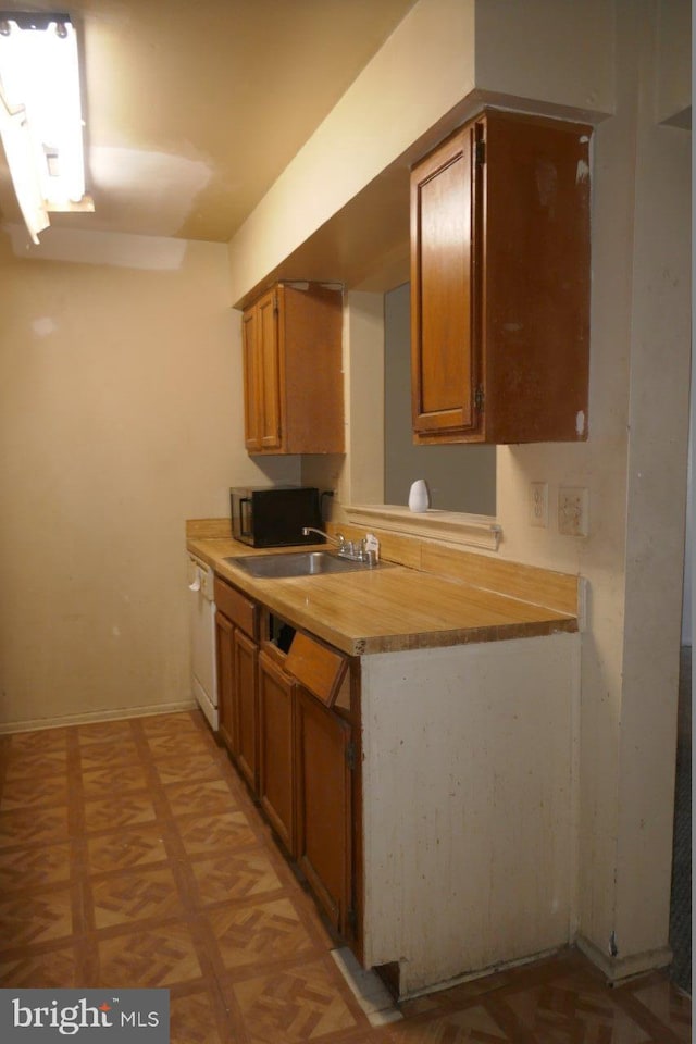 kitchen with white dishwasher, light parquet floors, sink, and wooden counters