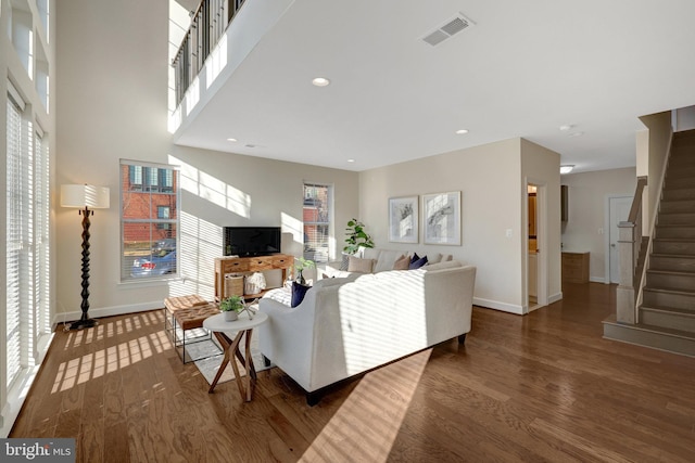 living area featuring baseboards, visible vents, stairway, dark wood-type flooring, and recessed lighting