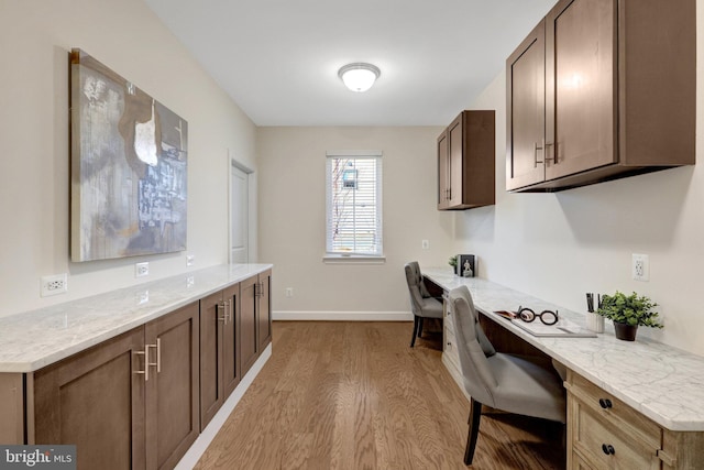 interior space featuring built in desk, light wood-style flooring, and baseboards