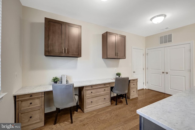 home office featuring dark wood-type flooring, built in study area, and visible vents