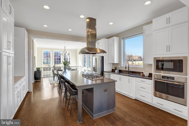 kitchen featuring stainless steel appliances, a kitchen island, white cabinetry, and island range hood