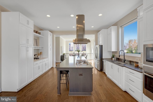 kitchen with appliances with stainless steel finishes, white cabinets, a kitchen island, and a sink