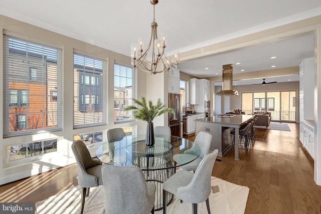 dining room with ceiling fan with notable chandelier, wood finished floors, and recessed lighting