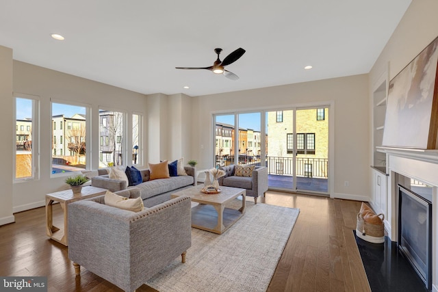 living room featuring a fireplace with flush hearth, a wealth of natural light, recessed lighting, and wood finished floors