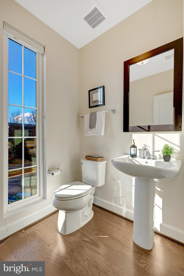 bathroom with visible vents, toilet, baseboards, and wood finished floors