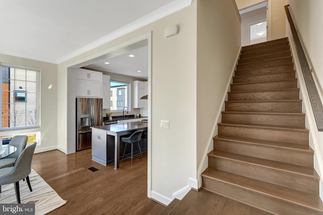 staircase featuring baseboards, ornamental molding, wood finished floors, and recessed lighting