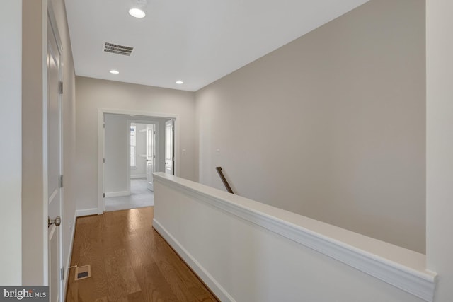 corridor with recessed lighting, visible vents, an upstairs landing, wood finished floors, and baseboards