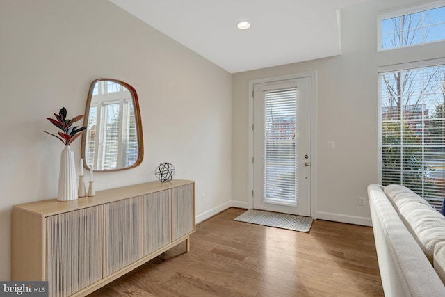 doorway featuring light wood-style flooring, a wealth of natural light, and baseboards