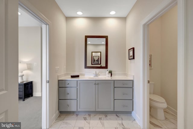 bathroom featuring baseboards, toilet, marble finish floor, vanity, and recessed lighting