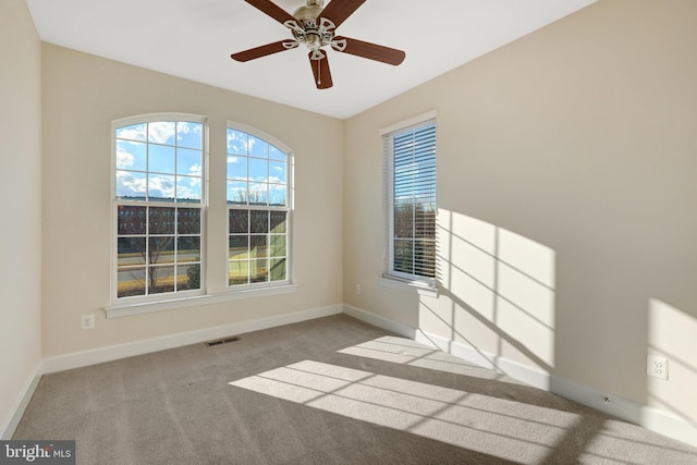 unfurnished room featuring light carpet, baseboards, visible vents, and a ceiling fan