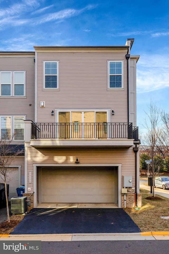 back of house featuring driveway, a balcony, and central air condition unit