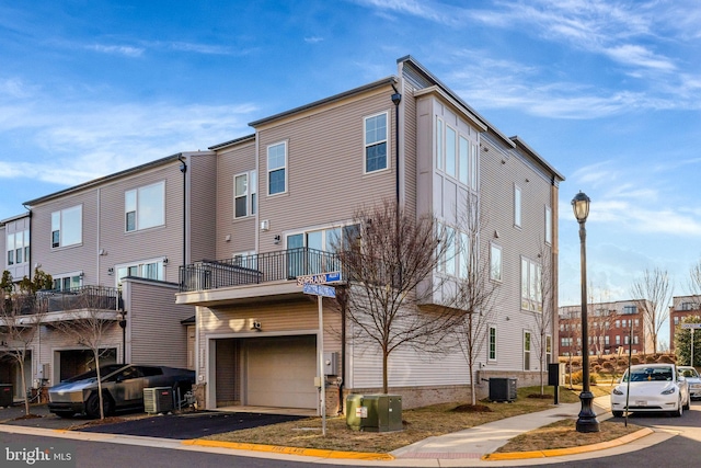 view of property featuring a garage, driveway, and cooling unit