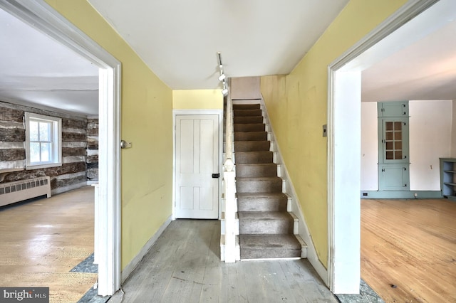 stairway featuring radiator, wood-type flooring, and track lighting