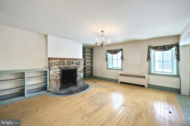 unfurnished living room with a stone fireplace, radiator, a wealth of natural light, and light hardwood / wood-style floors