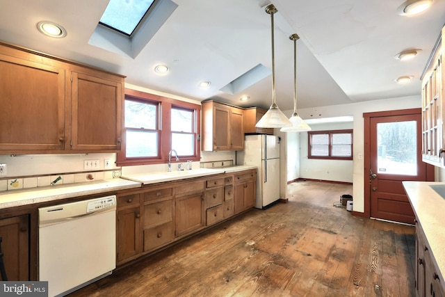 kitchen featuring sink, a skylight, hanging light fixtures, dark hardwood / wood-style flooring, and white appliances