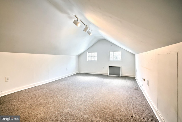 bonus room with vaulted ceiling and dark colored carpet