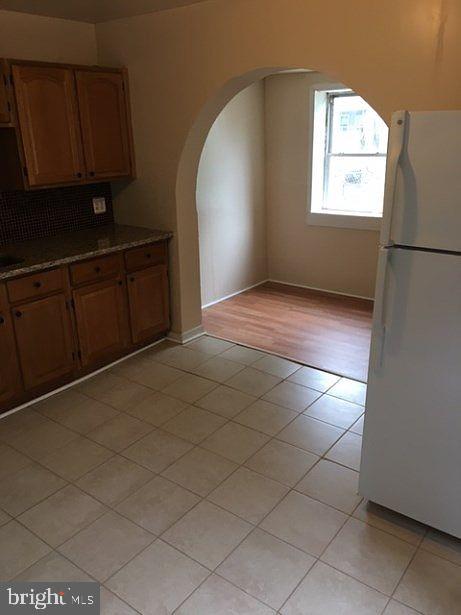 kitchen with decorative backsplash, light tile patterned floors, and white refrigerator