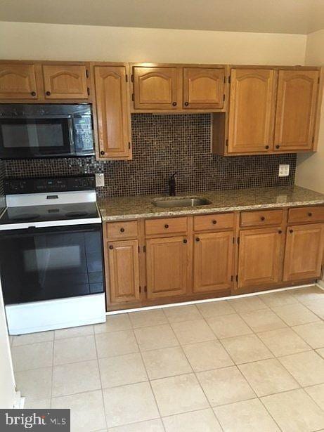 kitchen with decorative backsplash, electric stove, stone countertops, sink, and light tile patterned floors