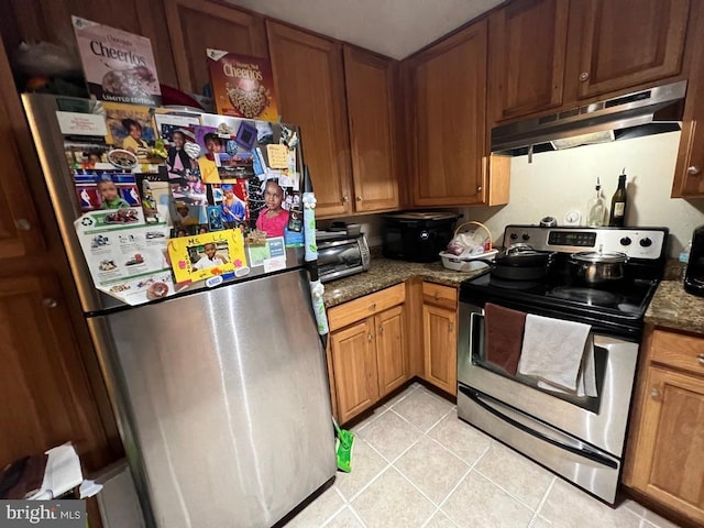 kitchen with stainless steel appliances, dark stone counters, and light tile patterned flooring