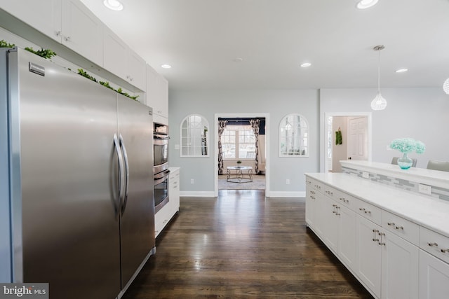 kitchen with hanging light fixtures, white cabinetry, appliances with stainless steel finishes, and dark wood-type flooring