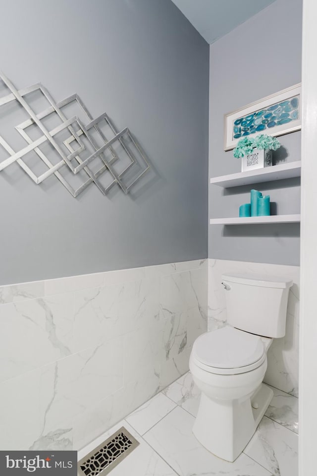 bathroom featuring toilet and tile walls