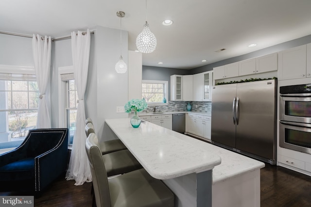 kitchen featuring pendant lighting, a breakfast bar area, white cabinetry, stainless steel appliances, and kitchen peninsula