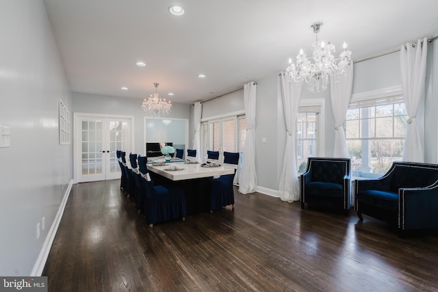 dining space with dark wood-type flooring, an inviting chandelier, and french doors