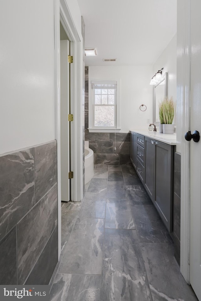 bathroom featuring tile walls, vanity, and a washtub