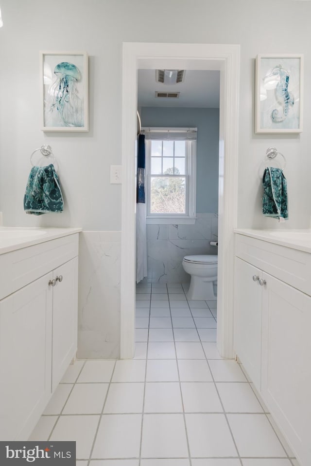 bathroom with tile patterned floors, toilet, tile walls, and vanity