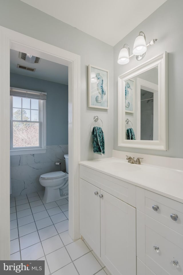 bathroom with tile patterned flooring, vanity, tile walls, and toilet