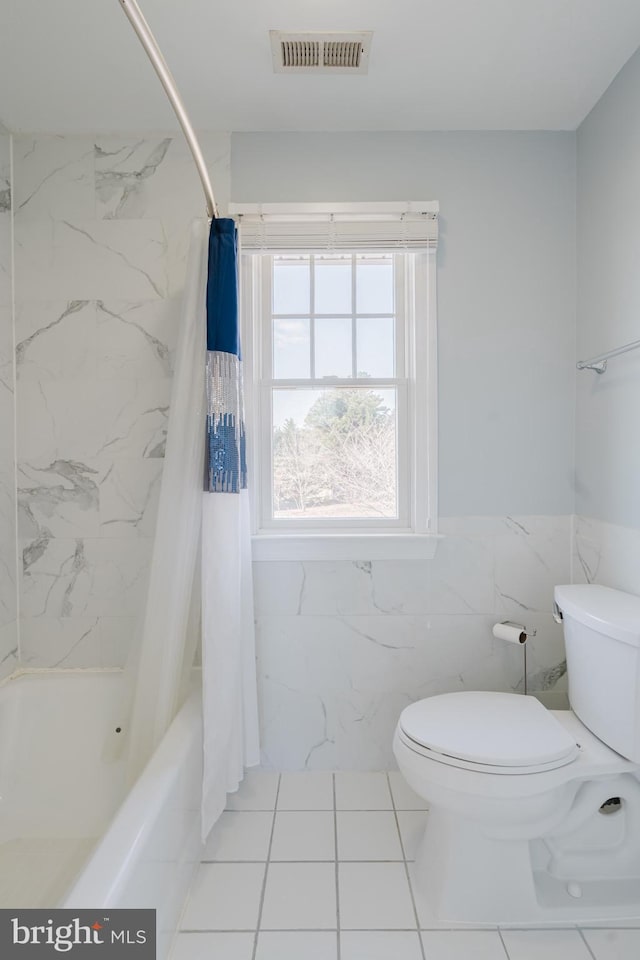 bathroom with tile walls, shower / tub combo, and toilet